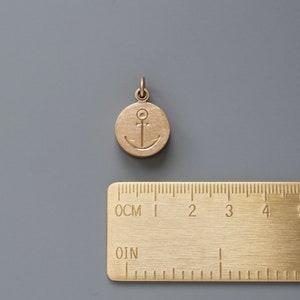 Pu&ograve; includere: Un ciondolo in metallo dorato con un design a forma di ancora. Il ciondolo &egrave; rotondo e ha una superficie liscia. Misura circa 2,5 cm di diametro.
