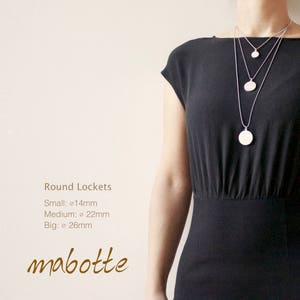 Pu&ograve; includere: Tre collane d'argento con medaglioni rotondi di diverse dimensioni. I medaglioni sono vuoti e le collane sono sovrapposte. Il testo "Round Lockets" e "mabotte" &egrave; visibile nella parte inferiore dell'immagine.
