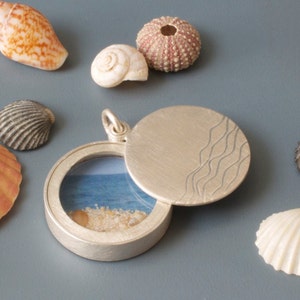 floating glass locket filled with seashells and waves design