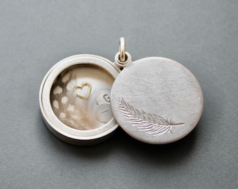 secret message locket filled with silver letter plates, a tiny feather and a golden heart