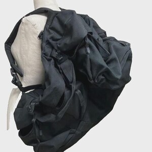 May include: A black backpack with multiple compartments and adjustable straps. The backpack is made of a durable fabric and features a drawstring closure on the main compartment. It has several exterior pockets and a padded back panel for comfort.