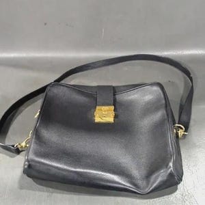 May include: Black leather shoulder bag with a rectangular shape and a gold-colored clasp. The bag has a long, adjustable strap and gold-toned hardware. The bag is a classic design.
