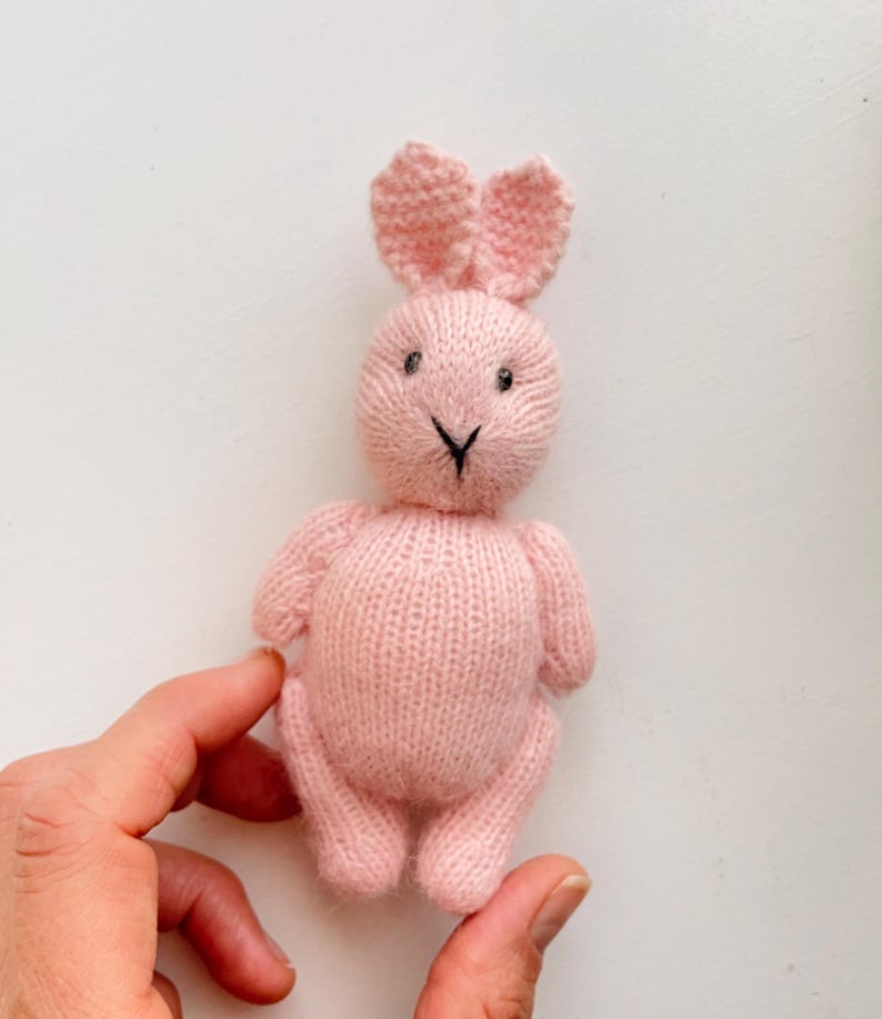 May include: A pink knitted bunny rabbit toy with black eyes and a black nose.