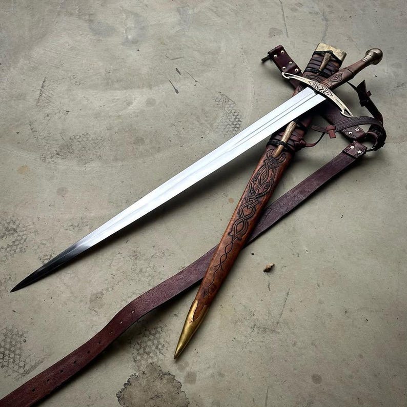 May include: A steel sword with a cross-shaped guard and a metallic pommel, accompanied by a brown leather scabbard featuring intricate embossed knotwork patterns, a brass tip, and attached leather straps for carrying the weapon securely.