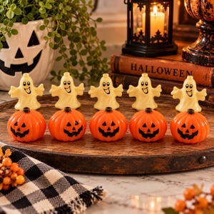 May include: A set of five small, cream-colored ghost figurines with smiling faces and five small, orange pumpkin figurines with black jack-o'-lantern faces, all arranged in two rows on a round, dark brown wooden tray.