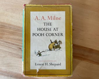 May include: A vintage copy of "The House at Pooh Corner" by A.A. Milne, with illustrations by Ernest H. Shepard. The book cover features a yellow border, the title in red, and a charming illustration of Pooh Bear.