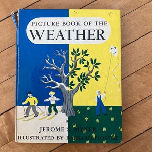 May include: A vintage children's book titled "Picture Book of the Weather" with illustrations of a tree, children skiing, and a child flying a kite. The book cover is blue, yellow, and green.