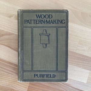 May include: A vintage green book titled "WOOD PATTERN-MAKING" by PURFIELD. The book cover features a black and white illustration of a woodworking tool.