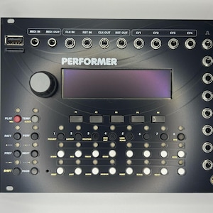 May include: Black electronic music device labelled "PERFORMER", featuring numerous input/output sockets, buttons, a screen, and a USB port. Designed for music production and performance, it has a sleek, modern design.