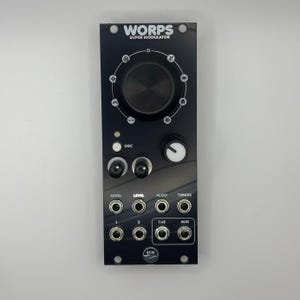 May include: Black electronic music synthesizer module with the text "WORPS SUPER MODULATOR". It features a large central knob, smaller knobs, and various input/output jacks. The module has a sleek, modern design with white text and accents.