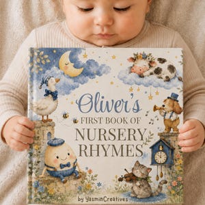 May include: A hardcover book titled Oliver's First Book of Nursery Rhymes by YasminCreatives. The cover features watercolor illustrations of a crescent moon, a cow on a cloud, a duck, a dog with a trumpet, a cat playing a violin, and a clock.