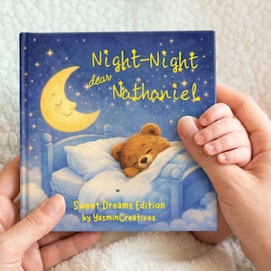 Puede incluir: Un libro infantil titulado "Night-Night dear Nathaniel" con una cubierta azul que presenta un oso de peluche durmiendo, una luna creciente sonriente y estrellas. El libro está sostenido por unas manos.