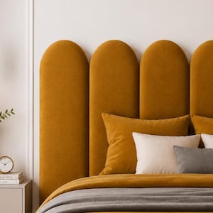 Può includere: Una testiera imbottita color senape con un design ad arco. Il letto è adornato con cuscini abbinati e una coperta grigia. Un comodino contiene un orologio, libri e un vaso con verde. Una lampada a sospensione dorata è appesa sopra.