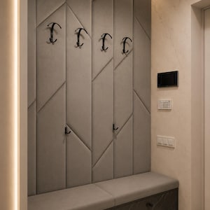 May include: A contemporary hallway with a grey upholstered bench and a wall-mounted coat rack. The wall has a geometric design with black hooks. The bench is above dark cabinets with a marble pattern. Overhead lighting illuminates the space.