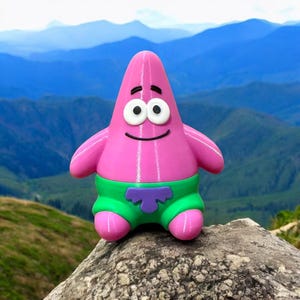 May include: A pink Patrick Star figurine with a smiling face, white eyes, and black eyebrows. The figurine wears green shorts with a purple design. The background features a mountain range.