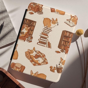 May include: A cream-colored tablet case featuring a repeating pattern of cartoon corgis wearing glasses and reading books. The corgis are depicted in various poses, including reading on a stack of books and relaxing in a chair. The case also has a black border.