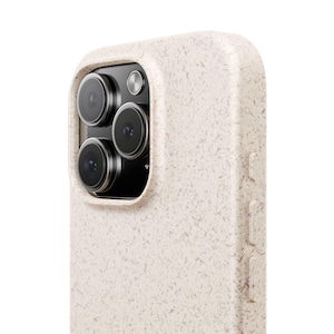 May include: Close-up of a beige speckled phone case with a camera cutout. The case has a textured surface and covers the side buttons. The phone's camera lenses are visible within the cutout.