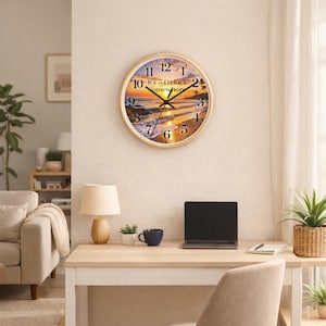 May include: Round wall clock with a light wood frame. The clock face features a beach scene with a sunset and the text "It's 5 O'clock Somewhere". The clock hands are black.