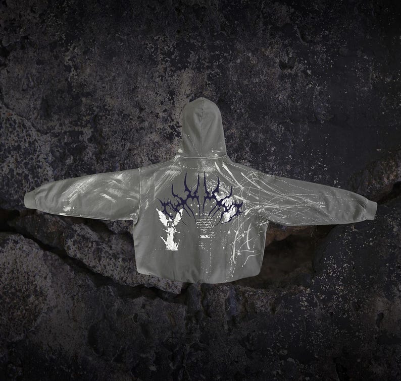 May include: A grey hooded sweatshirt featuring a dark purple stylised graphic across the upper back, a white winged figure illustration on the lower left, and white splatter patterns extending across the right side of the garment.