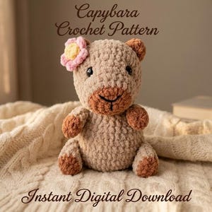 Könnte beinhalten: Ein hellbraunes gehäkeltes Capybara-Plüschtier mit einer rosa-gelben Blume auf dem Kopf, dunklen Augen und einem gestickten Mund. Der Text oben lautet Capybara Crochet Pattern und der Text unten lautet Instant Digital Download in brauner Schrift.
