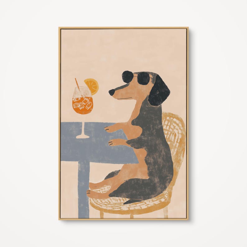 May include: A framed art print featuring a dachshund wearing sunglasses, seated at a table with a cocktail. The dog is black and tan, sitting on a wicker chair. The drink has ice cubes and an orange slice. The table is blue.
