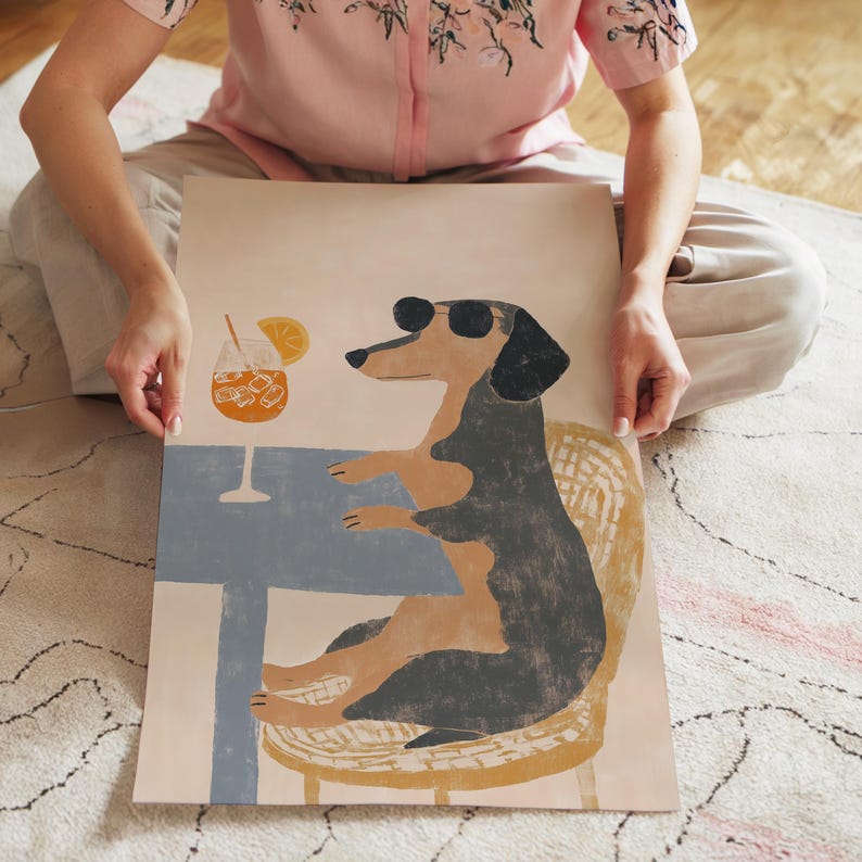 May include: A whimsical illustration of a dachshund wearing sunglasses, seated at a table with a cocktail. The dog is depicted in black and tan, with a blue table and a cocktail glass with ice and an orange slice.
