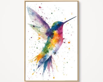 May include: Watercolor painting of a hummingbird in flight, framed in a light wood. The bird is depicted with vibrant colors including blue, purple, orange, and green. Splatter effects add to the artistic style. The background is white.