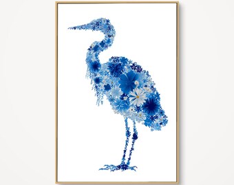 May include: A framed art print featuring a blue heron silhouette composed of various blue floral elements. The artwork is set against a white background, with a light brown frame. The heron's form is detailed with shades of blue.
