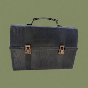 Puede incluir: Una fiambrera negra vintage con textura acanalada. La fiambrera tiene un asa negra y dos cierres met&aacute;licos de color &oacute;xido. La fiambrera es rectangular y parece estar hecha de pl&aacute;stico.