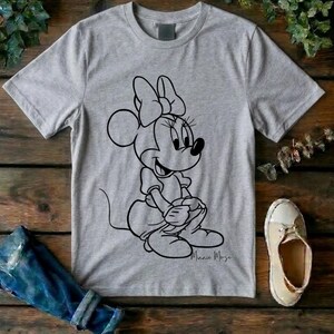 May include: A heather gray short-sleeved t-shirt featuring a black line art graphic of Minnie Mouse sitting down. The character is depicted with her signature bow and dress. Below the graphic, the name Minnie Mouse is written in a cursive script.