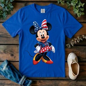 May include: A royal blue short-sleeve t-shirt featuring a graphic of Minnie Mouse wearing a bow with a red, white, and blue star-spangled pattern, a blue top with the number 22, a red and white polka dot skirt, and yellow and red shoes.
