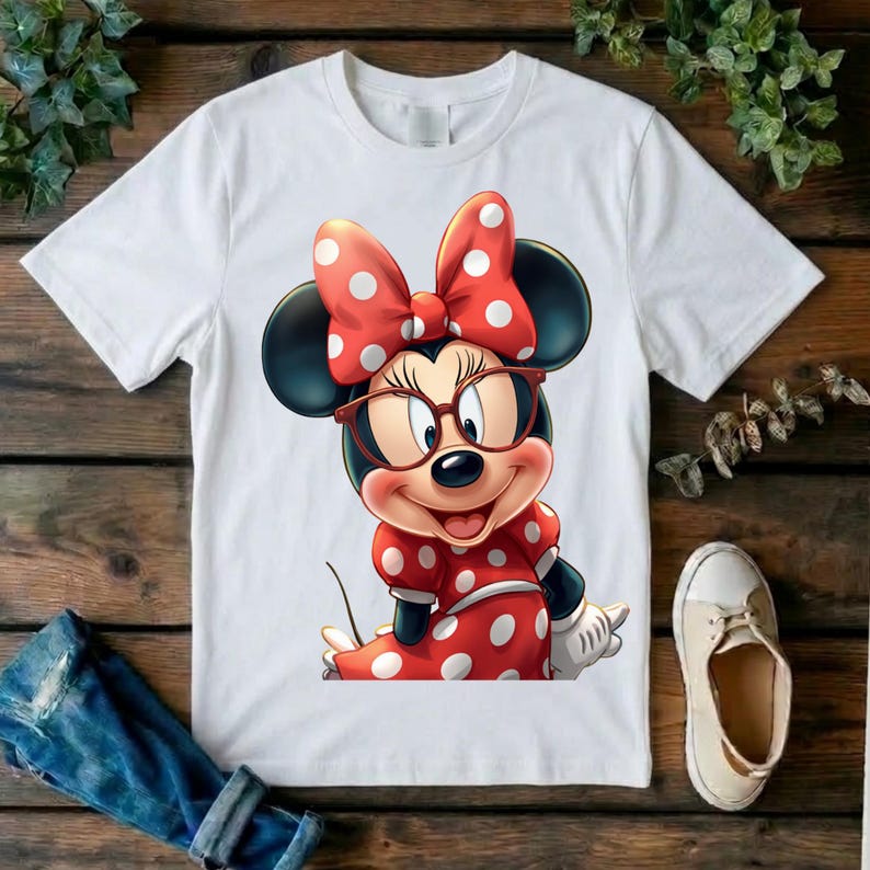 May include: A white short-sleeved t-shirt featuring a graphic print of a cartoon mouse character wearing red-rimmed glasses and a red dress with white polka dots, complemented by a matching red bow with white polka dots on the head.