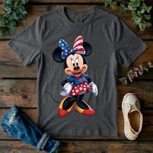 May include: A charcoal gray short-sleeve t-shirt featuring a graphic of Minnie Mouse wearing a red, white, and blue star-spangled bow, a blue top with the number 22, and a red skirt with white polka dots, paired with yellow and red shoes.