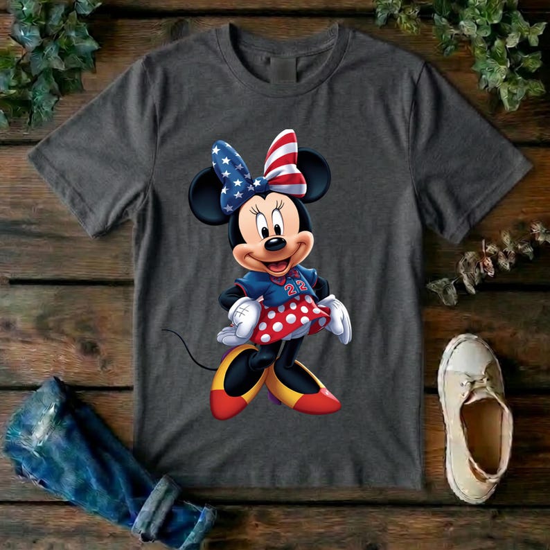 May include: A charcoal gray short-sleeve t-shirt featuring a graphic of Minnie Mouse wearing a red, white, and blue star-spangled bow, a blue top with the number 22, and a red skirt with white polka dots, paired with yellow and red shoes.