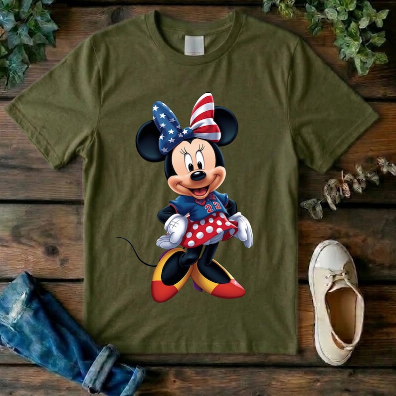 May include: An olive green short-sleeve t-shirt featuring a graphic of a cartoon mouse character wearing a bow with a red, white, and blue star-and-stripe pattern, a blue jersey with the number 22, a red polka-dot skirt, and yellow shoes.