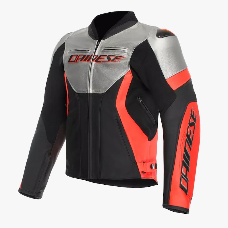 May include: Black, silver, and red motorcycle jacket with the brand name "DAINESE" in red lettering. The jacket has a stand-up collar, zippered pockets, and a fitted design. The shoulders and upper chest are silver, with red accents on the sleeves.