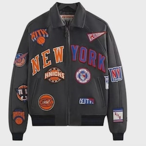 May include: A black leather jacket with multiple patches featuring the words "NEW YORK" and "KNICKS" in orange and blue. The jacket has a zip-up front, a collar, and ribbed cuffs and hem. Patches include basketballs and team logos.