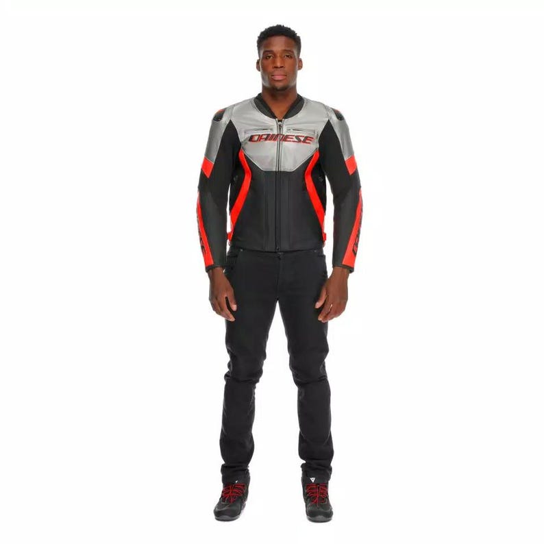 May include: Black and red motorcycle jacket with silver accents and the brand name "DAINESE" printed on the chest. The jacket has a zipper closure and is paired with black pants and black shoes.