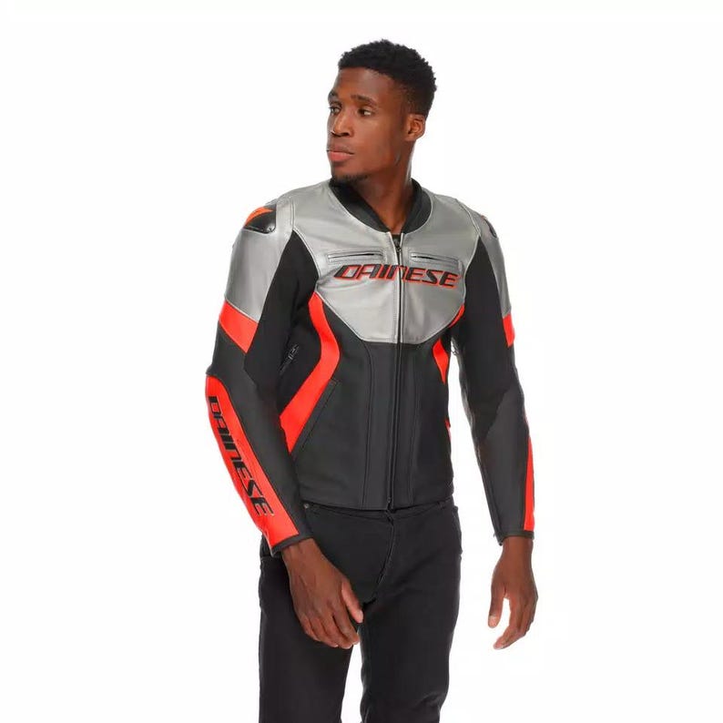 May include: A black and silver motorcycle jacket with red accents. The jacket features the brand name "DAINESE" in red on the chest and sleeves. The jacket has a full-length zipper and a stand-up collar.