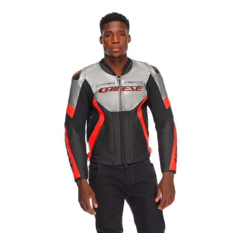 May include: A black, silver, and red motorcycle jacket with the brand name "DAINESE" in red lettering across the chest. The jacket has a zip-up front, padded shoulders, and red accents on the sleeves. The model is wearing black pants.