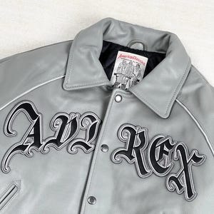 May include: A gray leather jacket with the text "AVL REX" in black script. The jacket has a collar, snap closures, and white trim. The label reads "American Classics."