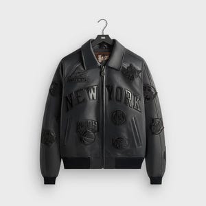 May include: Black leather bomber jacket with multiple patches and the words "NEW YORK" across the chest. The jacket has a zip-up front, a collar, and ribbed cuffs and hem. Patches include basketball-related designs and the Kith logo.