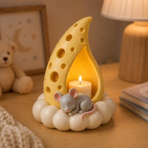 以下が含まれることがあります： 円形の穴が開いたスイスチーズの形をした黄色いキャンドルホルダー。ピンクの耳と尻尾を持つ小さな灰色のネズミが、白い雲の土台の上で眠っています。チーズの構造の中には、白いティーライトキャンドルが灯っています。