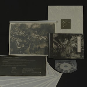 May include: A collection of Japanese media, including a CD, a booklet, and a box set. The items feature black and white imagery of nature scenes and Japanese text. The box set has the text "From Dust to Stars" on the front.