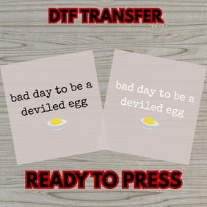 May include: Two DTF transfer sheets with the text "bad day to be a deviled egg" and a deviled egg graphic. The words "DTF TRANSFER" and "READY TO PRESS" are in red text.