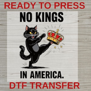May include: A black cat kicking a gold and red crown, with the text "NO KINGS IN AMERICA." The words "READY TO PRESS" and "DTF TRANSFER" are also present. The image has a cartoon style.