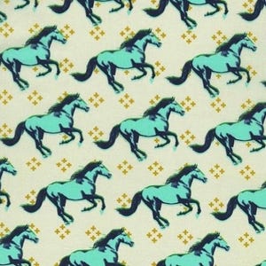 May include: A repeating pattern of running horses in teal and navy blue on a cream background. The horses are stylized with detailed manes and tails. Small gold cross-shaped designs are scattered throughout the background.