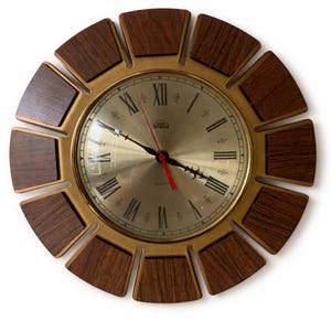 May include: A vintage wall clock with a gold-tone face and a dark wood-grain outer ring. The clock features Roman numerals and a red second hand. The clock's outer ring has a sunburst design.