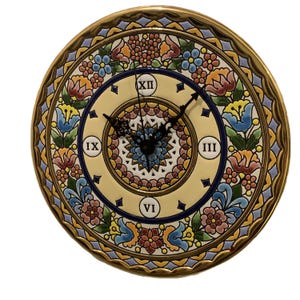 May include: A round ceramic wall clock featuring a cream-coloured centre with black Roman numerals XII, III, VI, and IX. The clock face is decorated with a vibrant, multi-coloured floral pattern in shades of blue, yellow, pink, and green, with a gold rim.