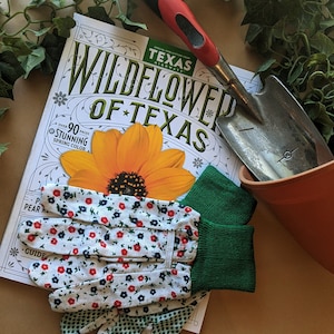 May include: A gardening kit with a pair of floral print gardening gloves, a small trowel, a terracotta pot, and a magazine titled "Wildflower of Texas" with a yellow flower on the cover.